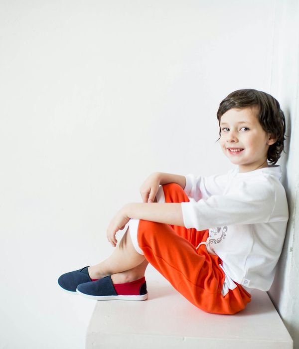Happy child doing a simple yoga pose in a bright room.